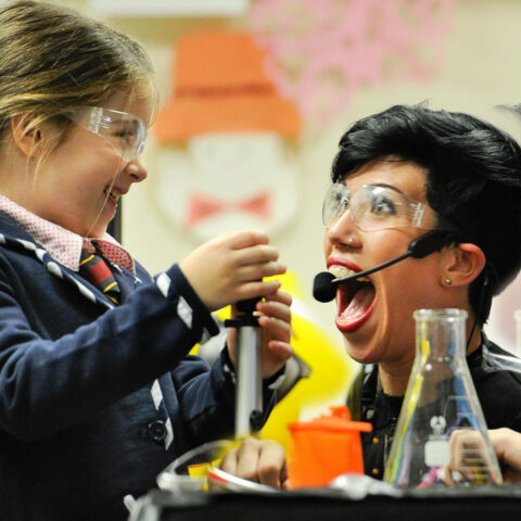 A science hero works on a science experience with a school girl.
